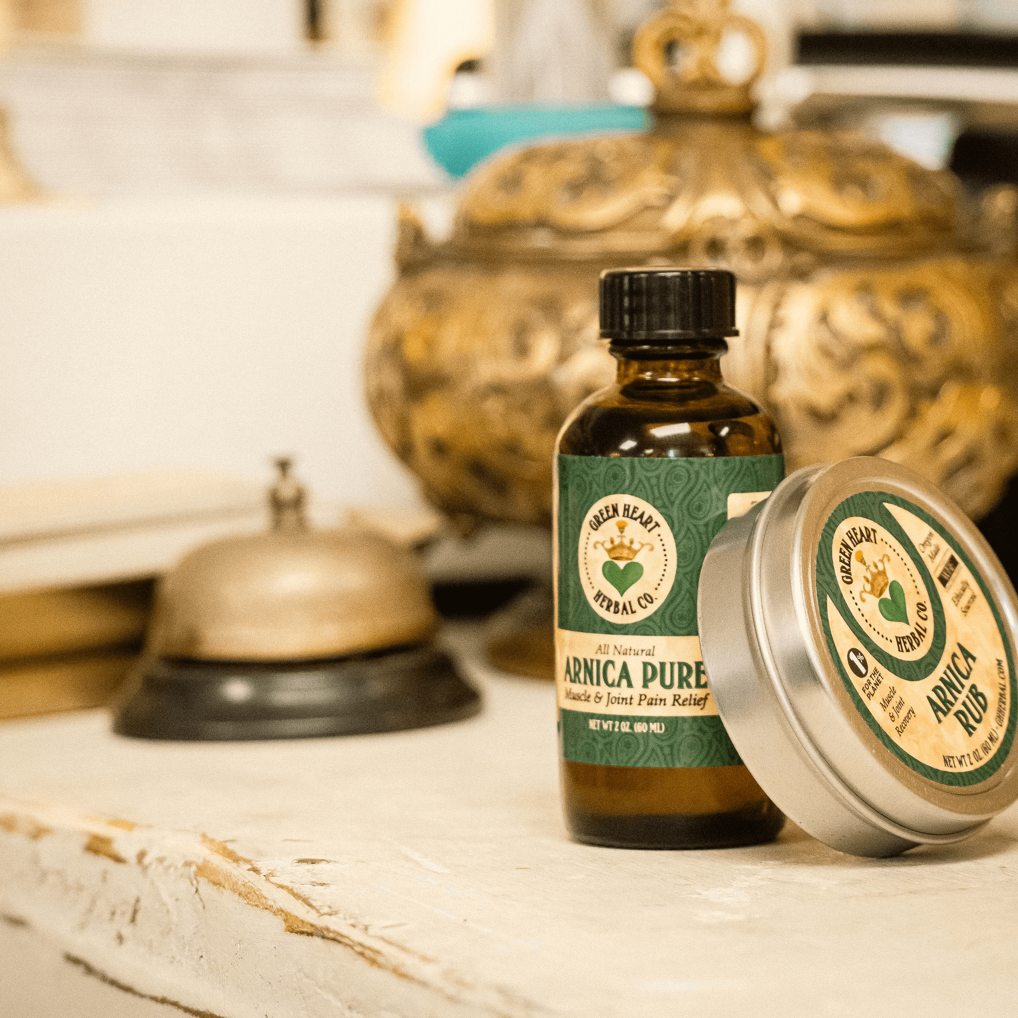 Arnica Pure natural pain relief oil bottle beside a vintage bell on a rustic table.